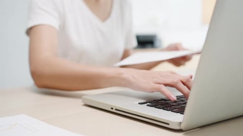 Businesswoman Working on Laptop with Financial Reports