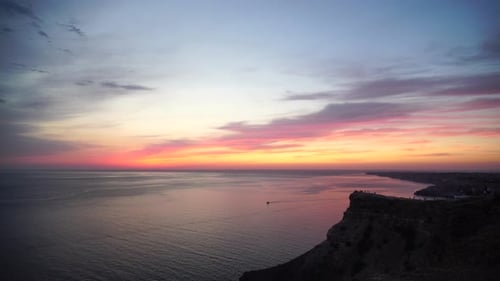 Panoramic Seascape View on Rocky Seashore Calm Azure Sea and Bright Sunset Lights Up Clouds in the