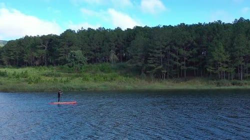 Aerial drone view of man is paddling on stand up paddleboarding in the mountain lakes