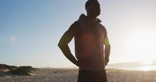 Athletic Man Stretching at Beach During Golden Hour