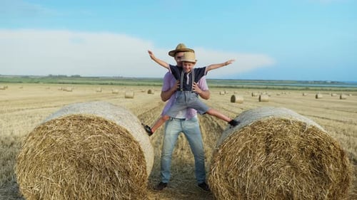 Fatherhood, Father with Son in Sun Hats Have Fun Playing on Field with Bales