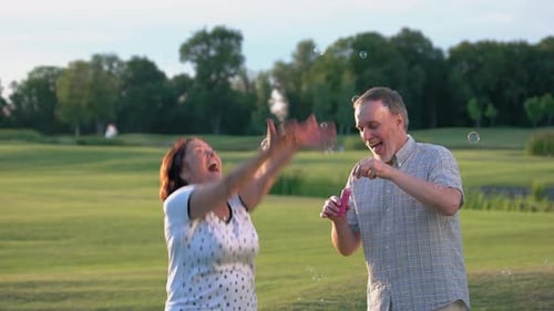 Mature Couple Playfully Blowing Bubbles in Rural Setting