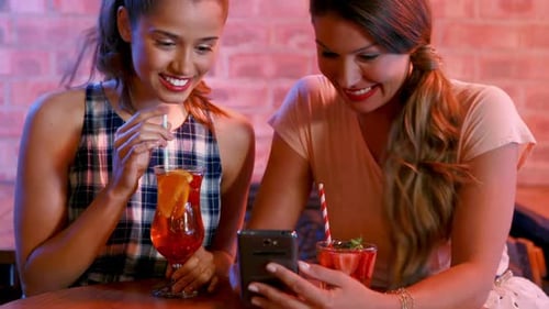 Young Women Enjoying Drinks and Smartphone Together