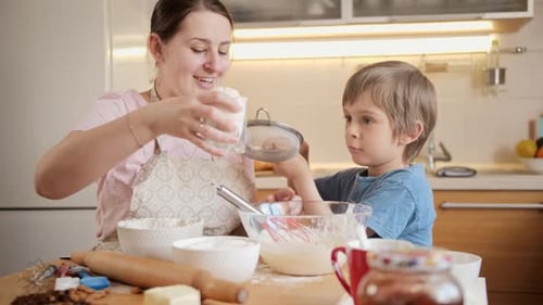 Woman and Child Baking Dough Together in Kitchen