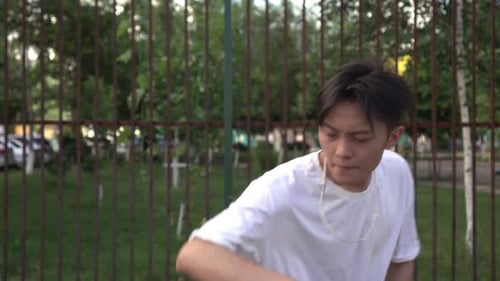 Young Man Dancing in Front of Fence