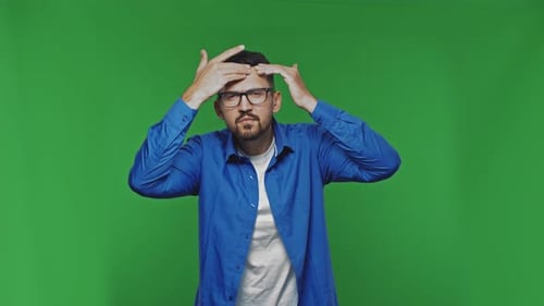 Man Standing in Front of Green Screen Touching Hair