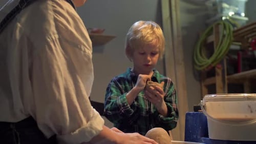 Boy Sculpts a Cup with His Hands in the Workshop