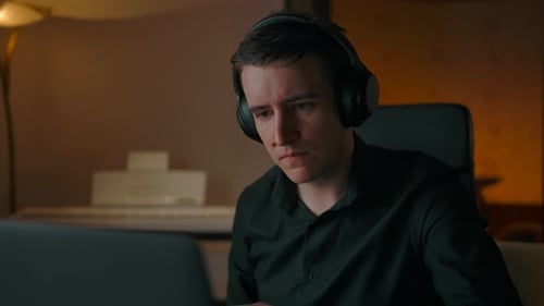 Man With Headphones Working At Computer at Home
