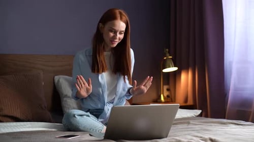 Red-Haired Woman Video Chatting on Laptop in Bedroom