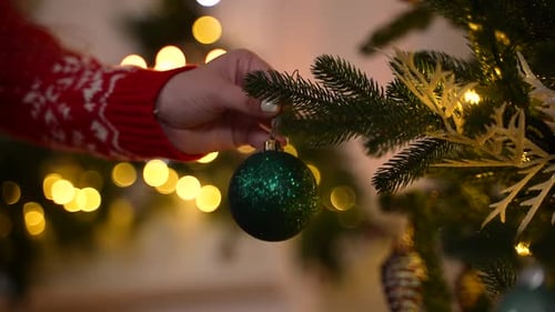 Hand Decorates Christmas Tree with Bauble Ornament