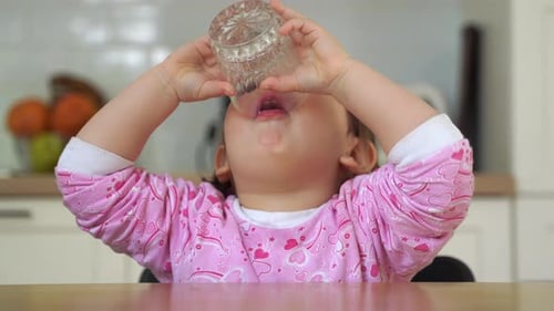 Une petite fille boit une compote de baies dans la cuisine. Alimentation saine des enfants, Vitamines