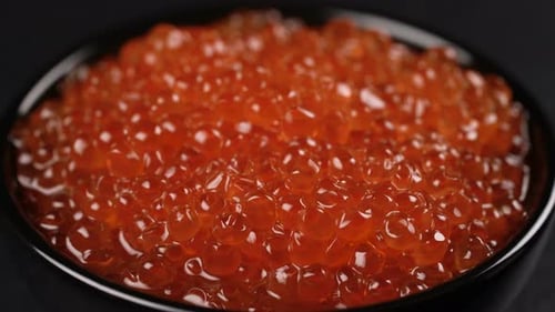 Red Caviar Rotated Over Black Background.