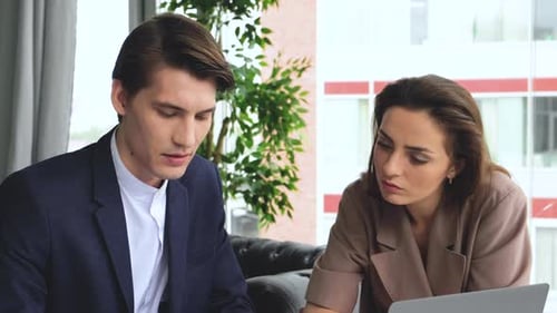 Young man and woman are working on a computer in a loft while discussing a project