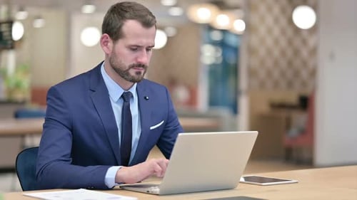 Sick Businessman with Laptop Coughing in Office
