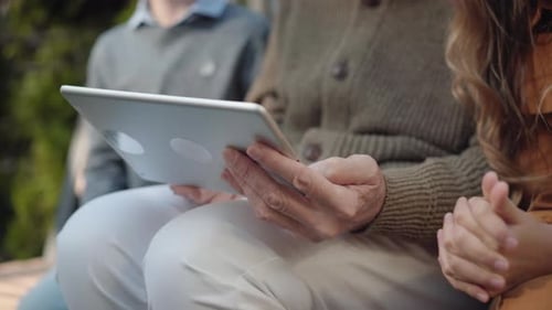 Unrecognizable Grandfather Sitting with Grandchildren Outdoors and Using Tablet. Male Senior
