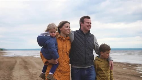 Happy and Friendly Family is Walking with Their Children on the Beach on Day Off