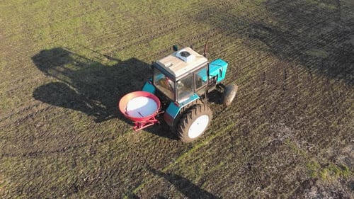 Tractor Spreading Artificial Fertilizers in Green Field. Farmer Fertilizing Arable Land with