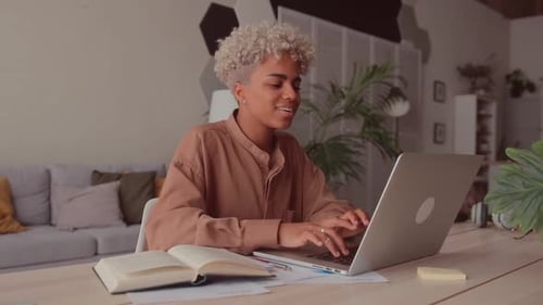 Woman works on laptop at her home desk