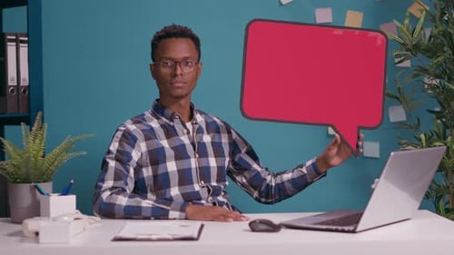 Man Holding Red Speech Bubble at Desk Indoors