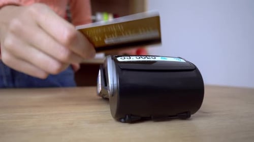 woman's hand holds plastic credit card in terminal. Payment by credit card.