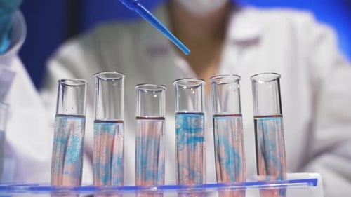 Laboratory Pipette Adding Blue Liquid to Test Tubes