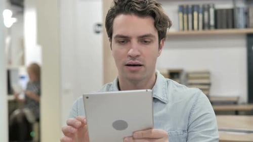 Man Excitedly Using Tablet Inside Office