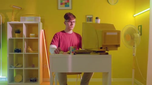 Junger Mann sitzt am Arbeitsplatz und scrollt mit der Computermaus