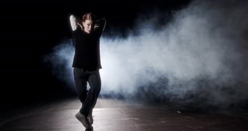 Teenage dancer performing hip hop dance in slow motion with strobe light and smoke background