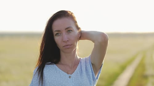 Woman in Beautiful Waving Dress Walks on the Meadow Happy Summer Vacation Sky at Sunset