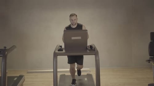 Wide Shot of Serious Sportsman Running on Treadmill in Gym. Front View Portrait of Caucasian