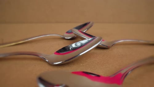 Shiny Silver Spoons on a Brown Surface
