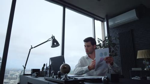 Focused Businessman Looking at Graphics on Document in Office