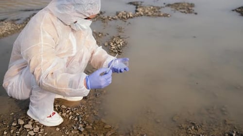 Scientist Takes Muddy Water Sample for Testing
