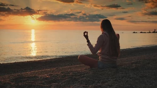 Mädchen meditiert vor Sonnenuntergang über dem Meer