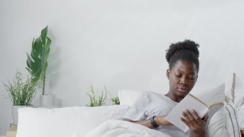 Woman Reading a Book in Bed