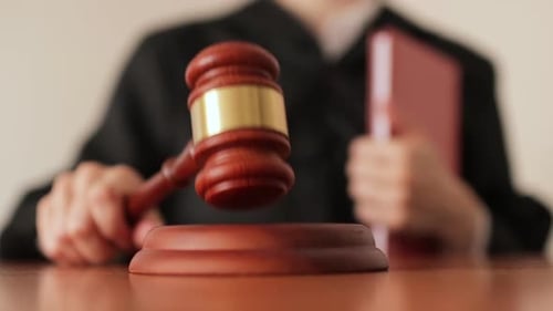 Judge's Hand Banging a Gavel in a Courtroom Close Up