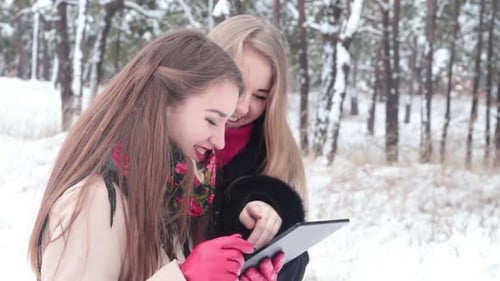 Two Women Using Tablet in Winter Forest