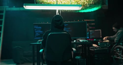 Schuss vom Rücken zum Hooded Hacker, der aus seinem Untergrund in Unternehmensdatenserver einbricht