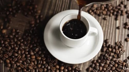 Coffee Cup and Coffee Beans. White Cup of Evaporating Coffee on the Table with Roasted Bean. Slow