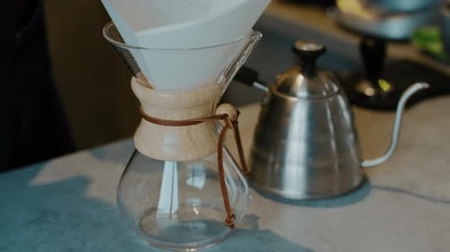 Barista making Filter coffee by spilling hot water through a layer of ground coffee on the filter