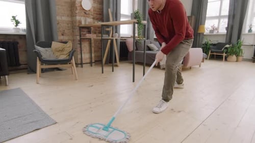 Young Man Dancing While Mopping the Floor