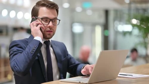 Man Answering Phone While Working At Computer