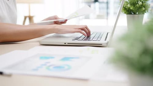 Young Adult Typing on Laptop at Desk Indoors