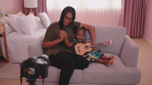 Woman and Child Playing Ukulele on Couch