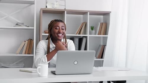 Smiling Woman Video Conferencing on Laptop in Office