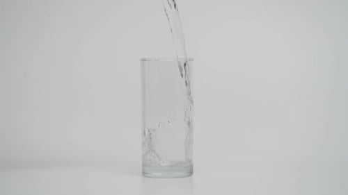 Water Being Poured into Glass on White Background