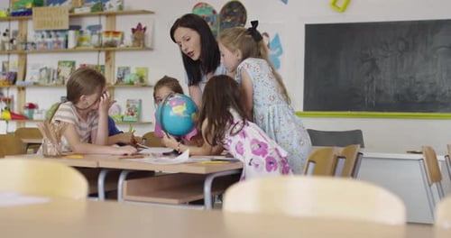 Female Teacher with Kids in Geography Class Looking at Globe