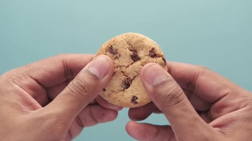Hand Breaking Chocolate Chip Cookie in Half
