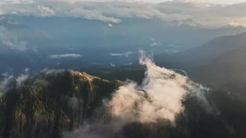 Flug über Wolken während des morgendlichen Sonnenaufgangs in den North Cascades Mountains (Luftaufnahme)