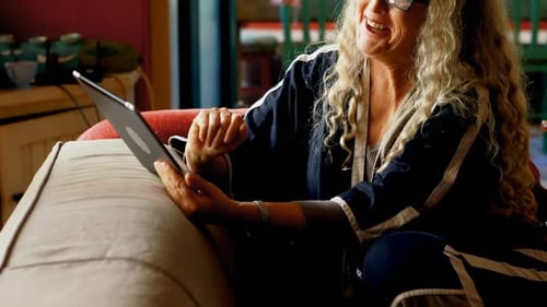 Woman Relaxing on Couch Using a Tablet Indoors